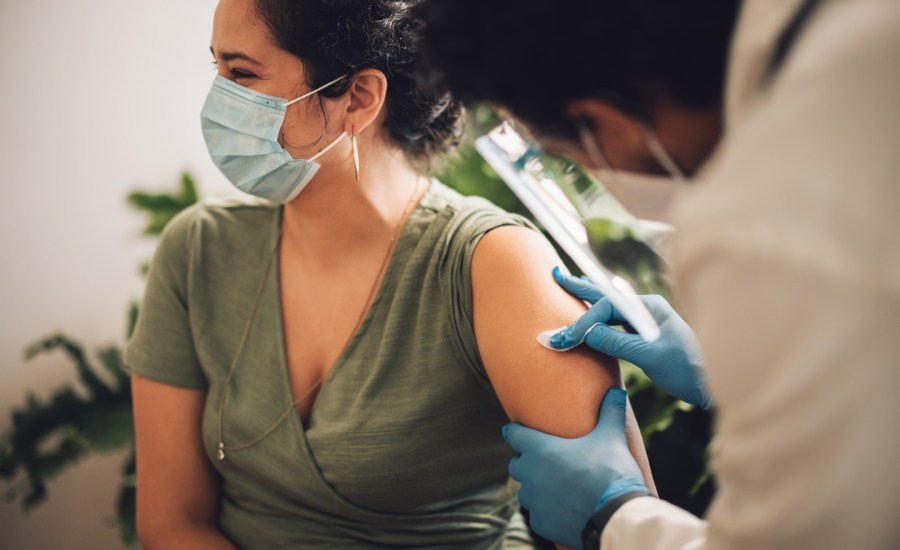woman wearing a face mask getting a shot in her left arm