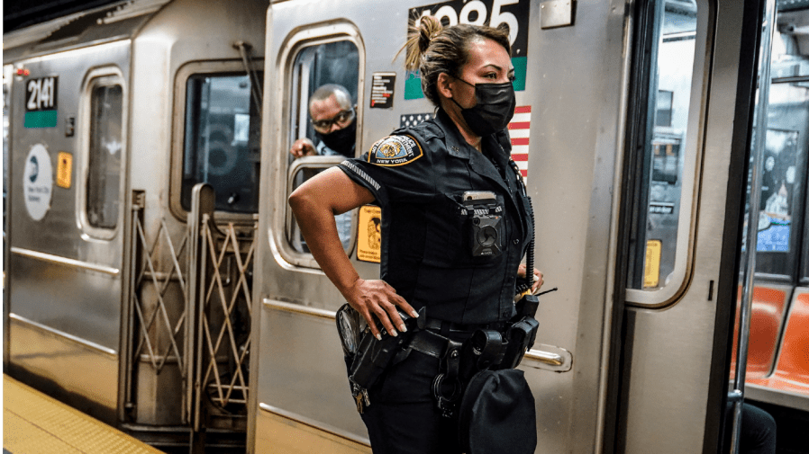 A New York City Police Department officer and a subway conductor look down the subway platform at the Grand Central Terminal subway station, in New York, on May 18, 2021.