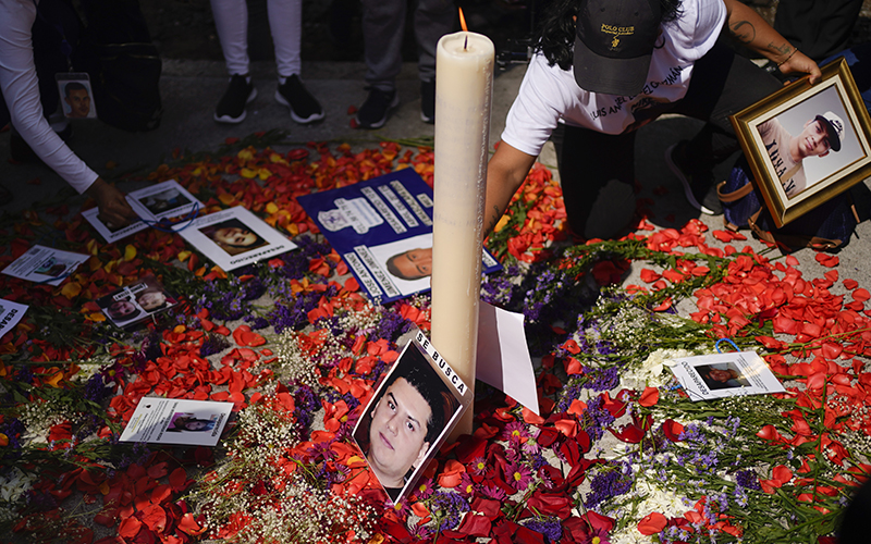 A person places a photo of a missing loved one on an improvised altar