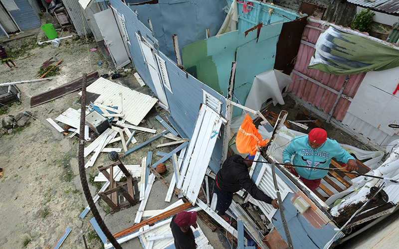 Residents replace a home’s roof that was torn off by Hurricane Fiona