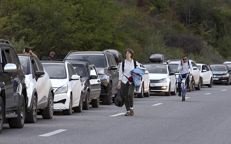 A young man walks past a line of cars outside the border crossing between Georgia and Russia