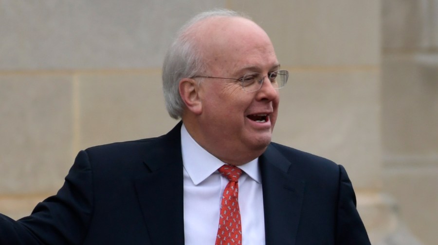 Karl Rove smiles as he looks off to the side.