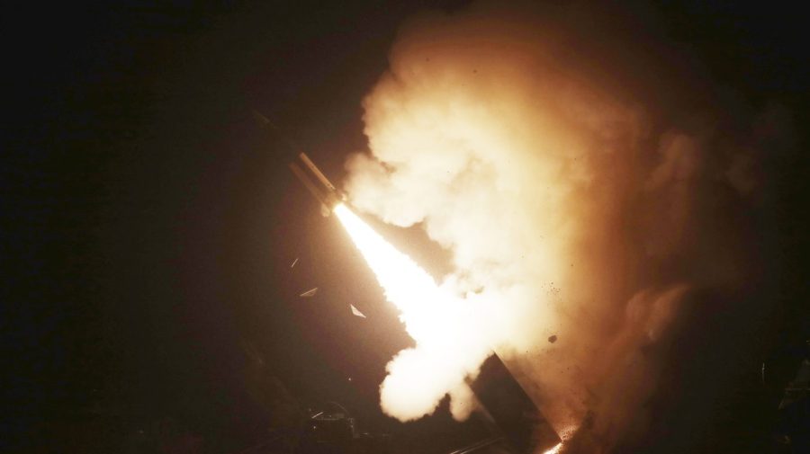 A plume of smoke is lit up against the dark sky as a missile is fired.