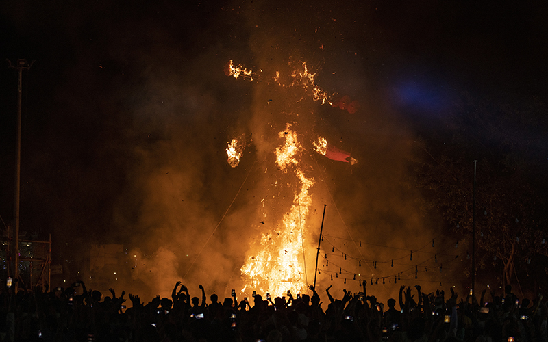 People watch the burning of effigies of demon king Ravana and his son and brother in New Delhi, India