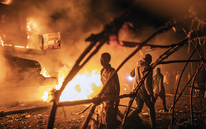 People walk by U.N. vehicles on fire in Goma, Democratic Republic of Congo