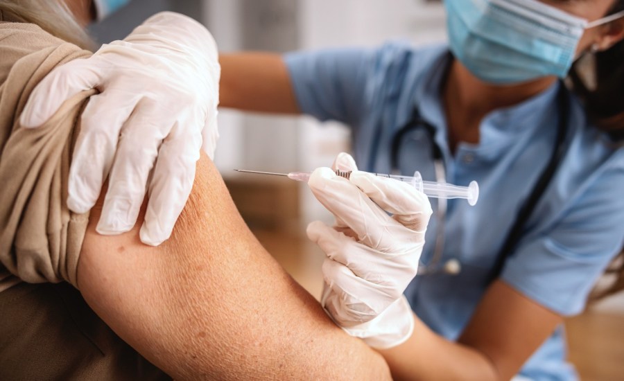 older adult getting a shot in the upper arm from a medical professional