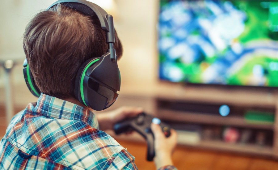 child playing video games, view from behind, blurred TV in background