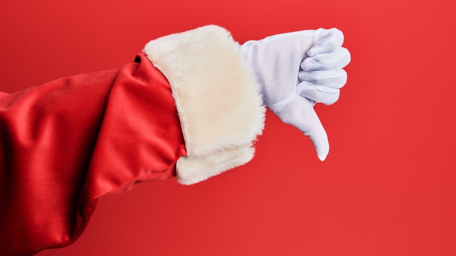 Hand of a man wearing santa claus costume and gloves over red background doing thumbs down rejection gesture, disapproval dislike and negative sign - stock photo