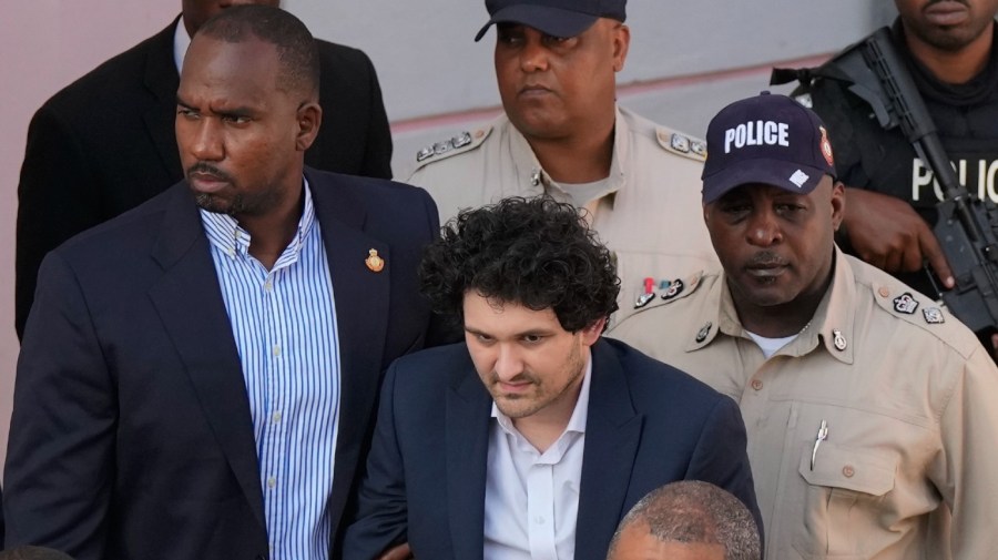 FTX founder Sam Bankman-Fried, center, is escorted out of Magistrate Court into a Corrections van, following a hearing in Nassau, Bahamas, Monday, Dec. 19, 2022.