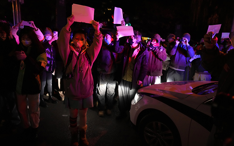 Protesters hold up blank papers and chant slogans as they march in protest in Beijing