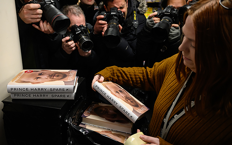 Members of the press gather round to take photographs of copies of "Spare" by Prince Harry