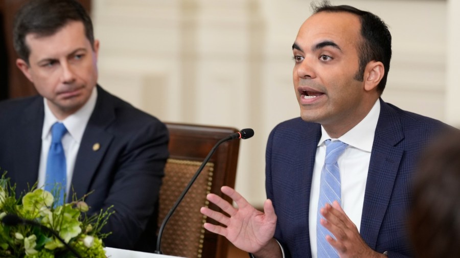 Rohit Chopra, director of the Consumer Financial Protection Bureau, speaks during a meeting while seated next to Pete Buttigieg.