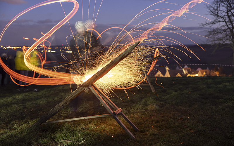 A man shakes a wooden disk to keep it on fire