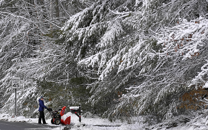 A resident clears snow from her driveway following a winter storm