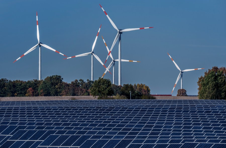 FILE - Wind turbines turn behind a solar farm in Rapshagen, Germany, Oct. 28, 2021. Germany has called for governments around the world to work on setting an ambitious target for renewable energy that would “ring in the end of the fossil fuel age” and help prevent dangerous global warming. (AP Photo/Michael Sohn, File)