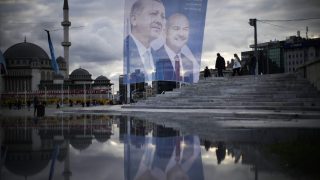 Pedestrians walk past a giant banner of Turkish President and People's Alliance's presidential candidate Recep Tayyip Erdogan, left, at Taksim square in Istanbul, Turkey, Wednesday, May 10, 2023. (AP Photo/Francisco Seco)