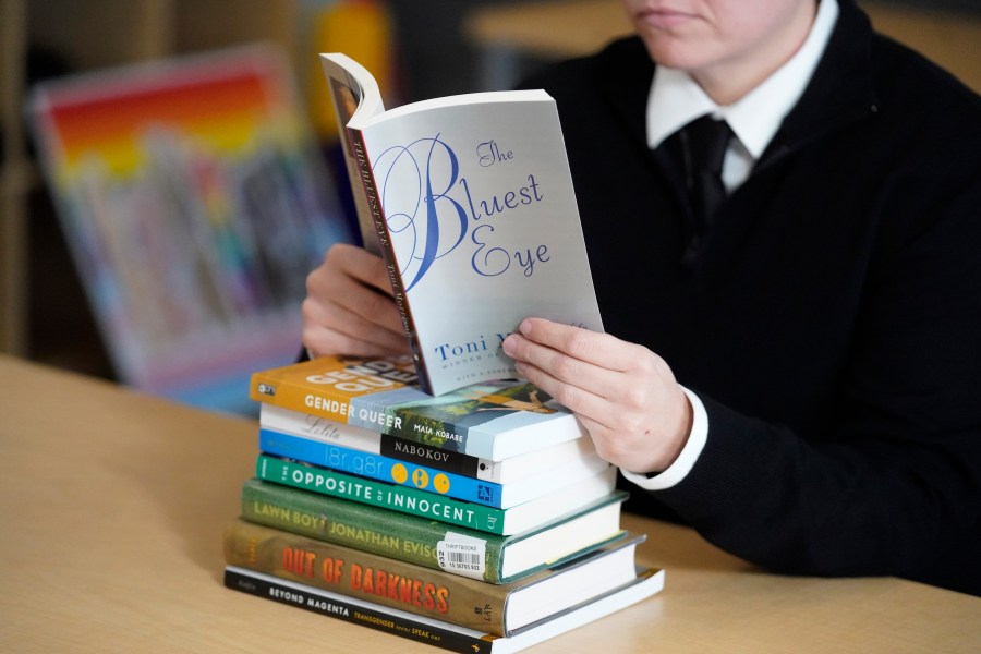 FILE - Amanda Darrow, director of youth, family and education programs at the Utah Pride Center, poses with books, including "The Bluest Eye," by Toni Morrison, that have been the subject of complaints from parents, on Dec. 16, 2021, in Salt Lake City. Publisher Penguin Random House and PEN America sued a Florida school district Wednesday, May 17, 2023, over its removal of books about race and LGBTQ+ identities, the latest opposition to a policy central to Gov. Ron DeSantis’ agenda as he prepares to run for president. Among the removed books are “The Bluest Eye” by Toni Morrison, “The Perks of Being a Wallflower” by Stephen Chbosky, “The Nowhere Girls” by Amy Reed and “Lucky” by Alice Sebold. (AP Photo/Rick Bowmer, File)