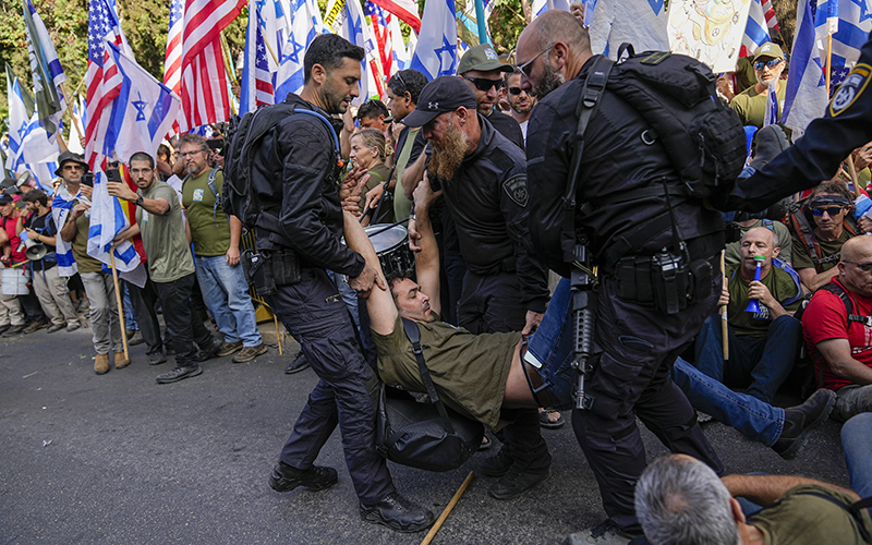 Israeli police officer carry away Israeli military reservists and other protesters