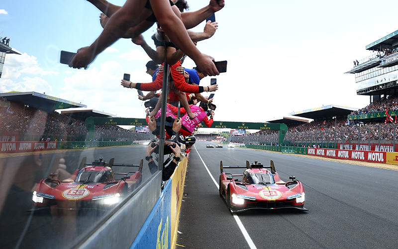 Attendees hold their phones over the railing to get a picture of the No. 51 Ferrari AF Corse Ferrari 499P of Alessandro Pier Guidi, James Calado and Antonio Giovinazzi