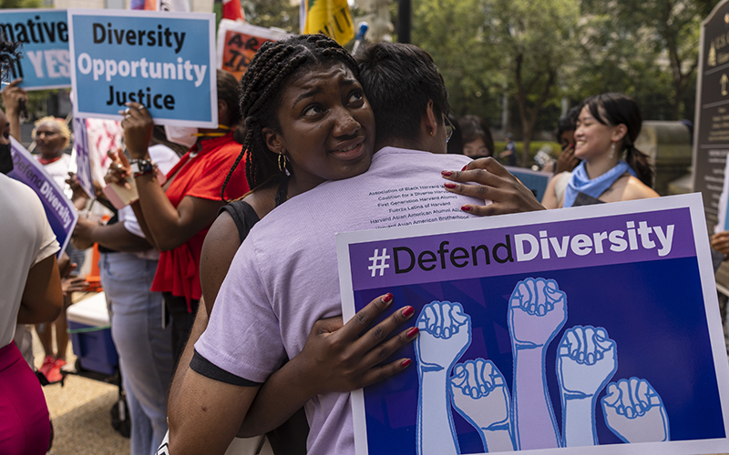 Nahla Owens, a student at Harvard University, hugs a fellow classmate while holding a sign that says "#DefendDiversity" outside the Supreme Court