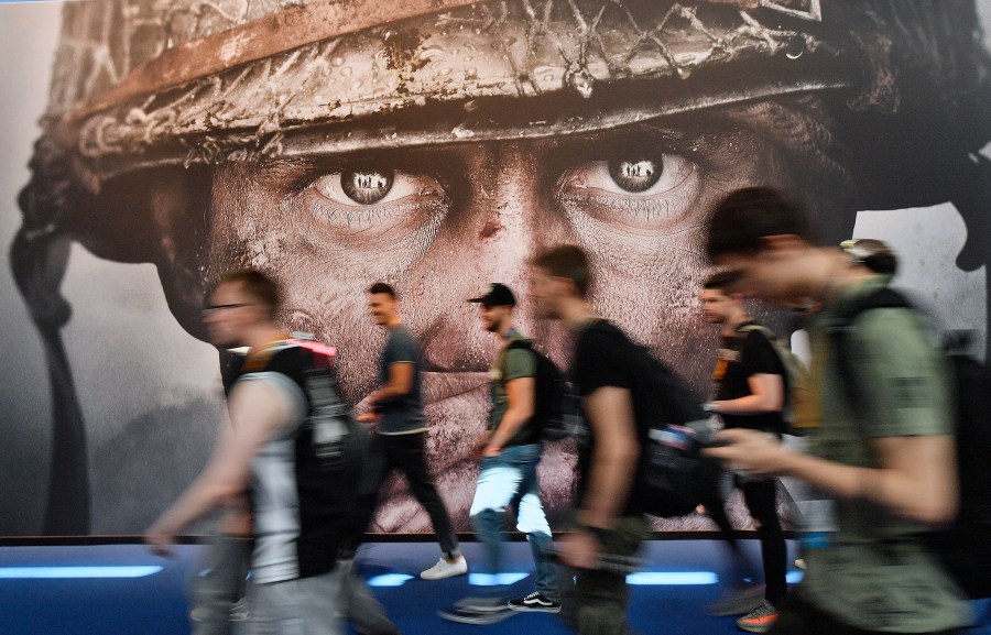 FILE - Visitors passing an advertisement for the video game 'Call of Duty' at the Gamescom fair for computer games in Cologne, Germany, Aug. 22, 2017. Microsoft has signed an agreement with Sony to keep the “Call of Duty” video game series on PlayStation following the tech giant’s acquisition of the video game maker Activision Blizzard. The announcement was made Sunday, July 16, 2023 in a Twitter post by Phil Spencer, who heads up Microsoft’s Xbox. (AP Photo/Martin Meissner, File)