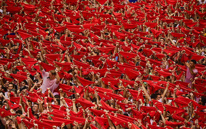 A crowd of participants hold up red kerchiefs at the opening of the San Fermín fiestas in Pamplona