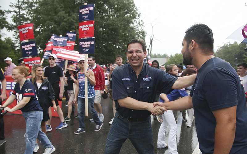 Republican presidential candidate and Florida Gov. Ron DeSantis shakes hands with a supporter as he walks in the Fourth of July parade