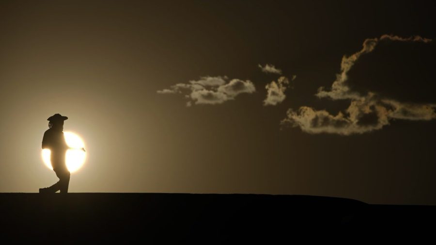 FILE - A person walks along a trail as the sun sets, Sunday, July 16, 2023, in Death Valley National Park, Calif. Human-caused global warming made July hotter for four out of five people on Earth, according to a new report issued Wednesday, Aug. 2, 2023, by Climate Central. (AP Photo/John Locher, File)