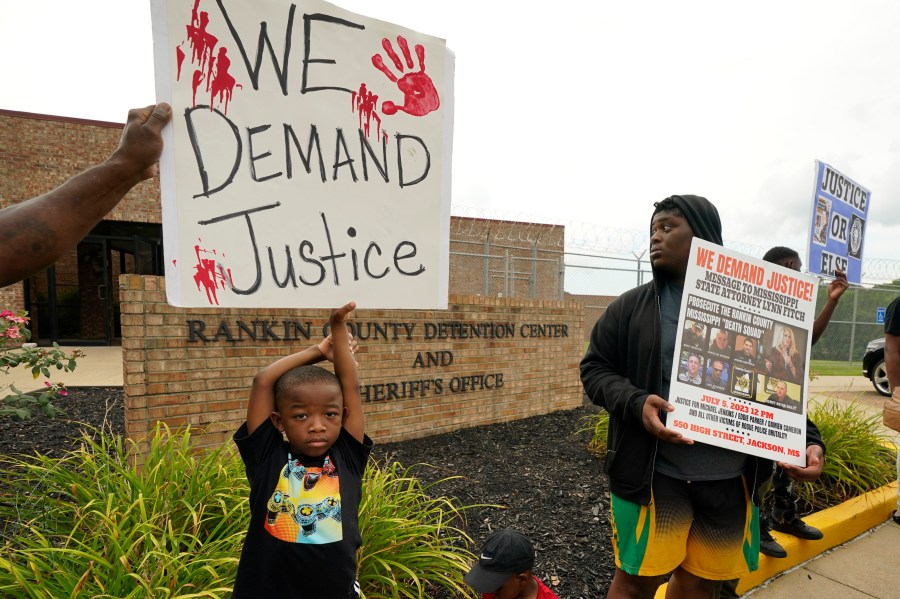 FILE - An anti-police brutality activist looks back at the entrance to the Rankin County Sheriff's Office in Brandon, Miss., Wednesday, July 5, 2023, as the group called for the termination and prosecution of Rankin County Sheriff Bryan Bailey for running a law enforcement department that allegedly terrorizes and brutalizes minorities. Six white former law enforcement officers in Mississippi have pleaded guilty to a racist assault on Michael Corey Jenkins and his friend Eddie Terrell Parker, who are Black. (AP Photo/Rogelio V. Solis, File)