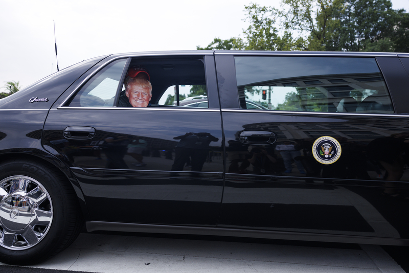 A limo with a Presidential seal and mask of former President Trump