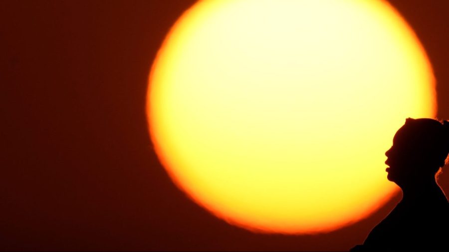 A woman's profile is silhouetted against the setting sun.