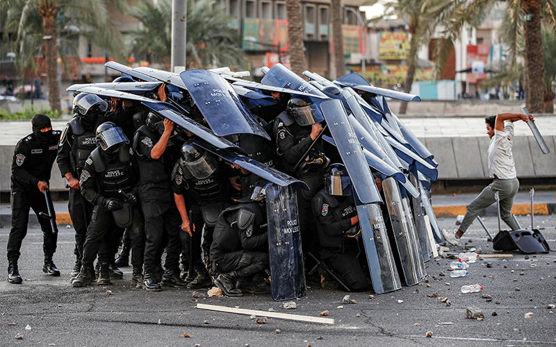 Iraqi riot-control police take cover behind their shields