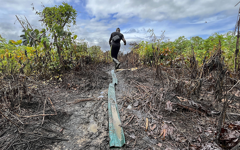 A man walk past an area of an illegal refinery