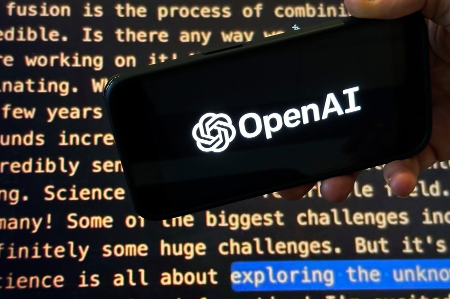 The OpenAI logo appears on a mobile phone in front of a screen showing a portion of the company website in this photo taken on Tuesday, Nov. 21, 2023 in New York. (AP Photo/Peter Morgan)