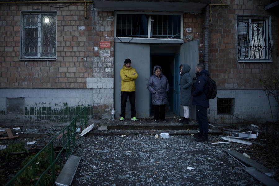 People stand amid glass from broken windows of their apartment building following a Russian drone attack in Kyiv, Ukraine, Saturday, Nov. 25, 2023. Russia launched its most intense drone attack on Ukraine since the beginning of its full-scale invasion on Saturday morning, military officials said. (AP Photo/Felipe Dana)
