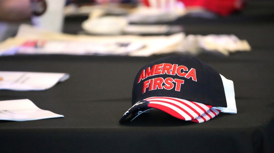 A hat with the words "America First" is displayed on a table during a conference on conspiracy theories about voting machines and discredited claims about the 2020 presidential election at a hotel in West Palm Beach, Fla., Saturday, Sept. 10, 2022.