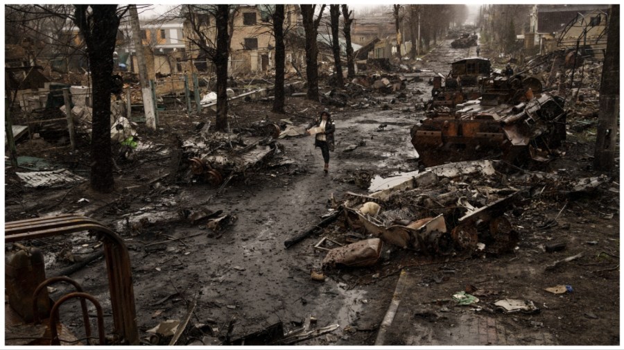 A woman walks amid destroyed Russian tanks in Bucha, in the outskirts of Kyiv, Ukraine, Sunday, April 3, 2022. (AP Photo/ Rodrigo Abd)