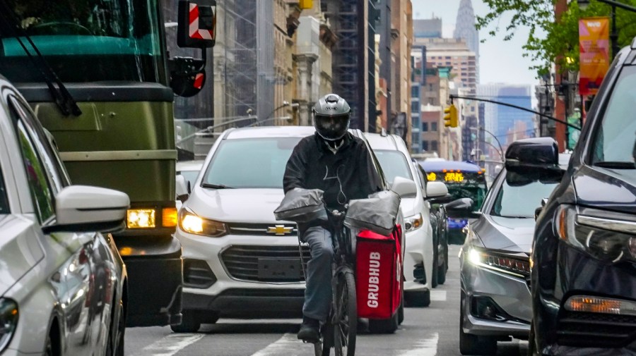 A food delivery worker rides through the a busy street in lower Manhattan, Friday, April 28, 2023, in New York.