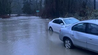 In this photo provided by Kira Mascorella, cars drive through flood waters in Granite Falls, Wash., Tuesday, Dec. 5, 2023. An atmospheric river has brought heavy rain, flooding and warm winter temperatures to the Pacific Northwest, closing rail links, schools and roads as it shattered daily rainfall and temperature records in Washington state. (Kira Mascorella via AP)