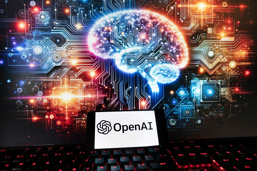The OpenAI logo is displayed on a cell phone with an image on a computer monitor generated by ChatGPT's Dall-E text-to-image model, Friday, Dec. 8, 2023, in Boston. Europe's yearslong efforts to draw up AI guardrails have been bogged down by the recent emergence of generative AI systems like OpenAI's ChatGPT, which have dazzled the world with their ability to produce human-like work but raised fears about the risks they pose. (AP Photo/Michael Dwyer)