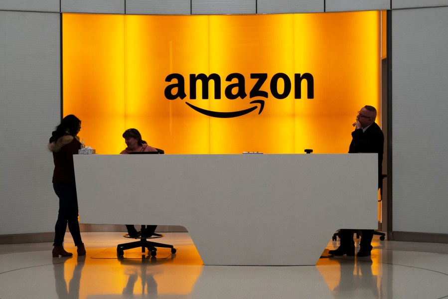 FILE - People stand in the lobby of Amazon offices on Feb. 14, 2019, in New York. Amazon won’t have to pay about 250 million euros ($273 million) in back taxes after European Union judges ruled in favor of the U.S. ecommerce giant, dealing a defeat to the bloc in its efforts to tackle corporate tax avoidance. (AP Photo/Mark Lennihan, File)