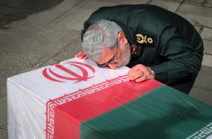 In this photo released by an official website of the office of the Iranian supreme leader, head of Iran's expeditionary Quds Force, Gen. Esmail Ghaani, places his face on the flag-draped coffin of Seyed Razi Mousavi, a high ranking Iranian general of the paramilitary Revolutionary Guard, who was killed in an alleged Israeli airstrike in Syria on Monday, at supreme leader's office compound in Tehran, Iran, Thursday, Dec. 28, 2023. (Office of the Iranian Supreme Leader via AP)