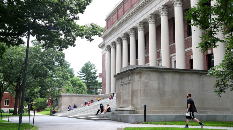 People sit on the steps of a campus building at Harvard University.