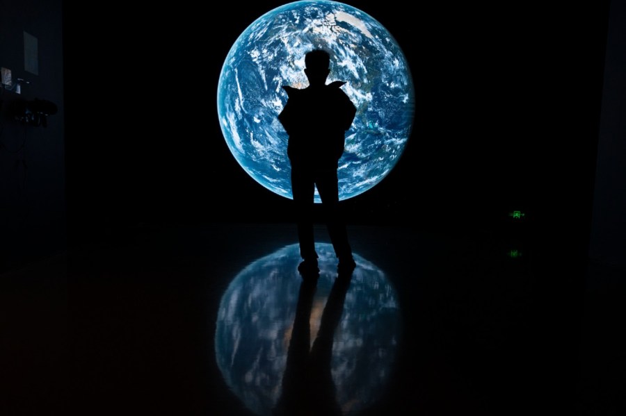 A visitor stands near a display showing earth during an exhibition about China's space program in Beijing, Thursday, Dec. 28, 2023.