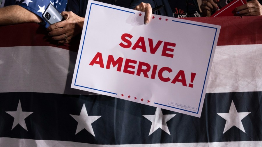 A Republican supporter holds a "Save America" sign at a rally for former President Donald Trump at the Minden Tahoe Airport in Minden, Nev., Saturday, Oct. 8, 2022.
