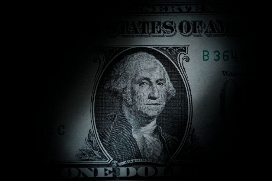 The likeness of George Washington is seen on a U.S. one dollar bill covered in shadow.