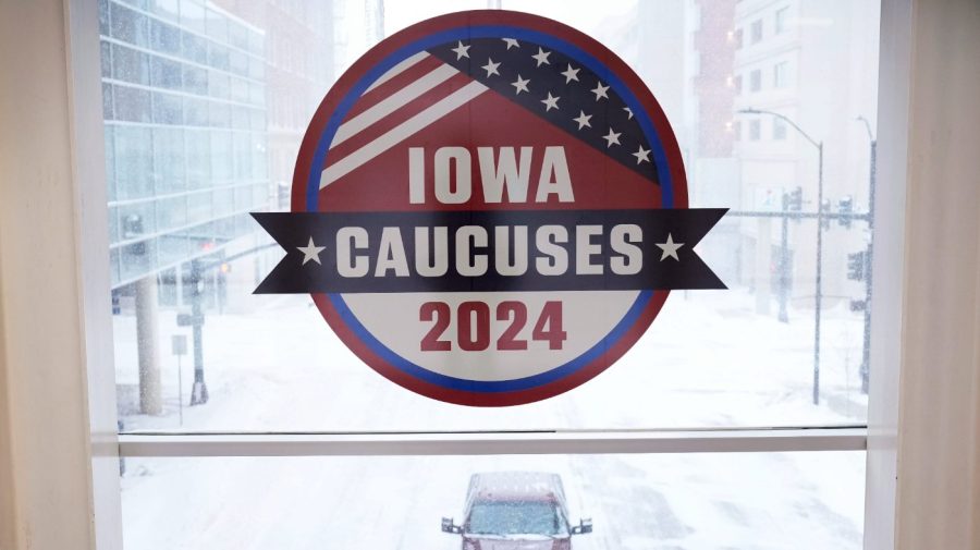 A pickup truck is driven down a snow covered road under an Iowa Caucus sign, Friday, Jan. 12, 2024, in downtown Des Moines, Iowa.