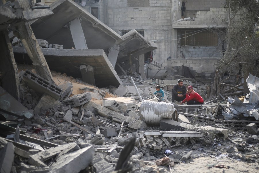 Palestinians sit by the destruction from the Israeli bombardment of the Gaza Strip in Rafah on Monday, Feb. 12, 2024.