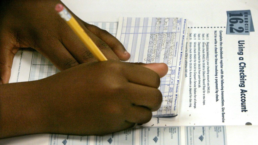 Shamya Davis, Ariel Community Academy sixth-grader, balances a checkbook ledger during his personal finance class at the corporate-sponsored school on Chicago's South Side.