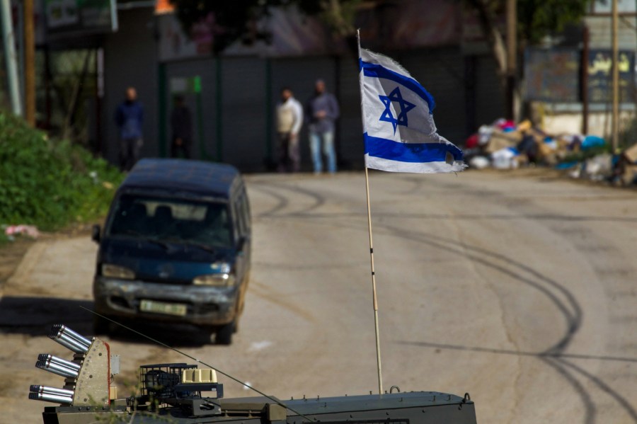 Israeli forces' vehicles are strategically positioned on a road as they conduct a raid on the al-Faraa camp for Palestinian refugees near Tubas city in the occupied West Bank on January 13, 2024.